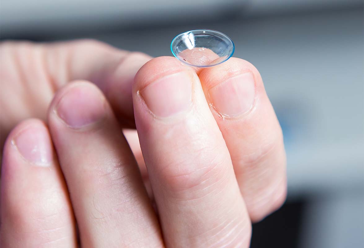 Heron Eyecare team member holding contact lens in fingers